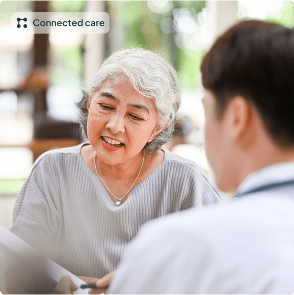 Elderly woman smiling and talking with a clinician outdoors