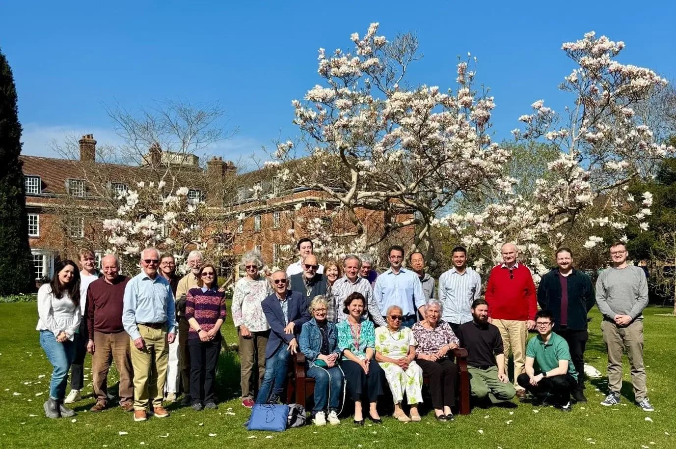 Group photo outdoors under blossoming trees for World Parkinson's Day